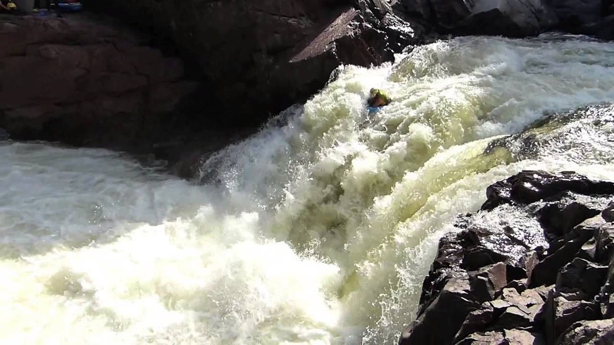 A rider dropping over a ledge in heavy whitewater on a Fluid Anvil riverboard, Rouge River, Quebec